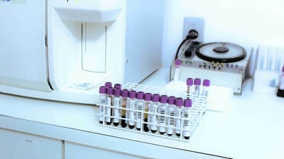 Rack of purple cap blood collection tubes staged in an analyzer bay, signaling PK and TK sample processing and biometrics workflows that support clinical pharmacology decisions at Crystal Bio Solutions.